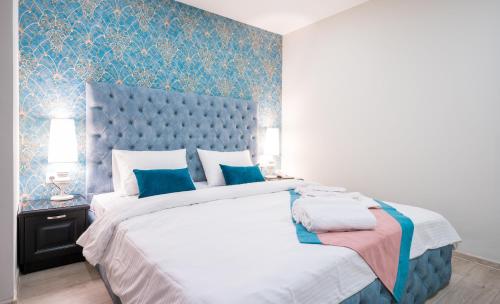 トビリシにあるCapitol Hotel By umbrellaのベッドルーム1室(青い壁紙の大型ベッド1台付)