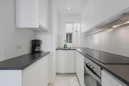 uma cozinha branca com armários brancos e bancadas pretas em Easy apartment in Fuengirola Downtown - Ref 28 em Fuengirola
