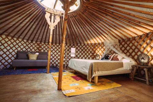 una camera da letto in una yurta con un letto e un divano di La Veleta Cádiz a Cadice
