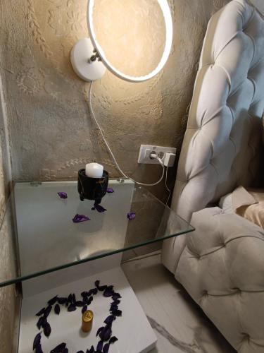 a glass table with a lamp and a chair at Jacuzzy Rooms Andjela in Subotica