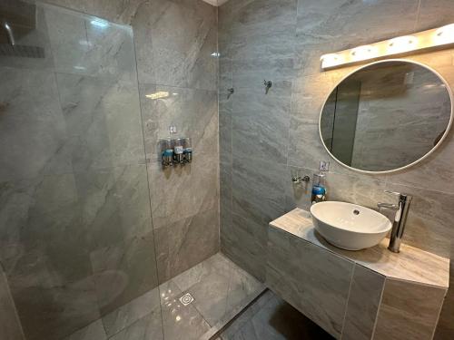 a bathroom with a sink and a shower with a mirror at Hotel Lujan in Piriápolis