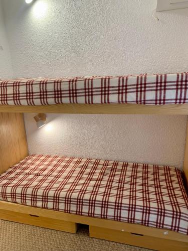 伊索拉 2000的住宿－Studio montagne gentianes，双层床的上方配有一张铺着拼盘的床单
