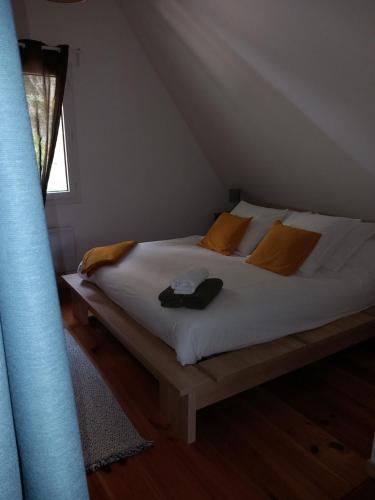a bedroom with a bed with orange pillows and a window at le petit bambou in La Roque-Gageac