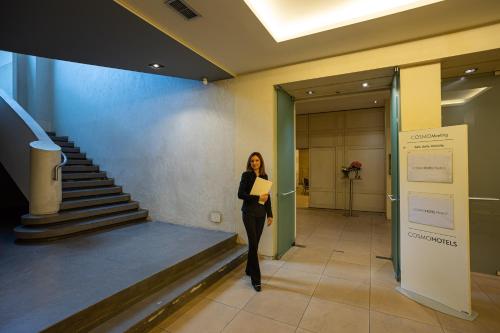 a woman standing in a hallway with a folder at Cosmo Hotel Palace in Cinisello Balsamo