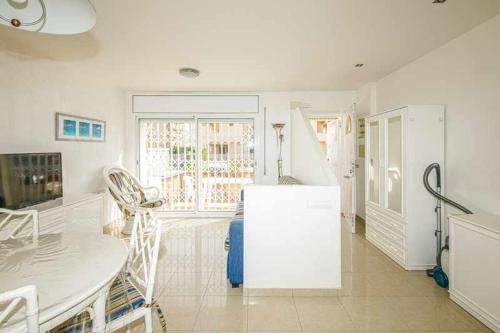 a white kitchen with a table and a refrigerator at 106casa bocana inmo apartaments roses in Roses
