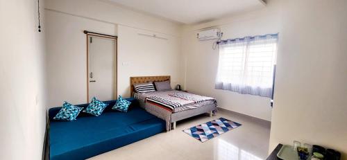 a room with a blue couch and a window at Rent On Comfort Luxury Room in Mysore