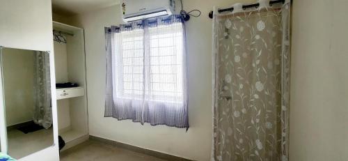 a bathroom with a window and a curtain at Rent On Comfort Luxury Room in Mysore
