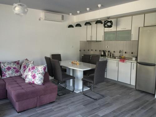 a living room with a purple couch and a kitchen at Bjelica Apartments Kotor in Kotor