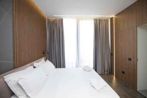 a bedroom with a white bed and a large window at Charm Hotel in Vlorë