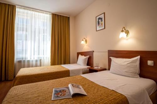 a hotel room with two beds with a newspaper on the bed at Primavera 2 Hotel in Pazardzhik