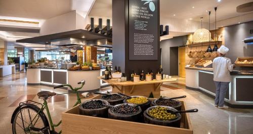 a person standing in a bakery with a table of food at Valamar Diamant Hotel in Poreč