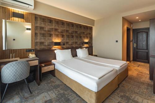 ソゾポルにあるKalithea Family Hotelの大きなベッドとデスクが備わるホテルルームです。