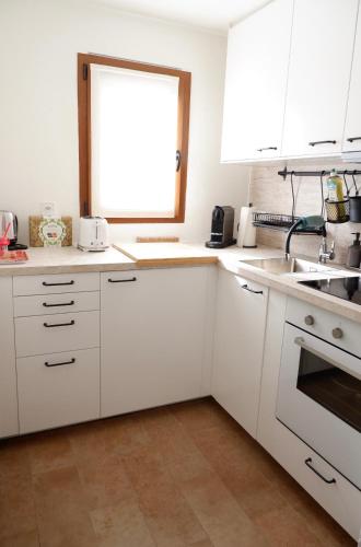 a kitchen with white cabinets and a sink and a window at La casetta Brè in Brè sopra Lugano
