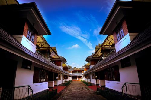an alley between two buildings with a blue sky in the background at Wetzlar Villas in Angamaly