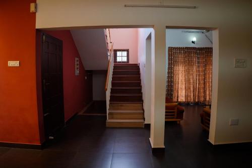 a hallway with stairs in a house with red walls at Wetzlar Villas in Angamaly