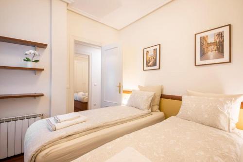 2 camas en una habitación con paredes blancas en APARTAMENTO EN EL CORAZÓN DE LA CIUDAD con PARKING PRIVADO, en San Sebastián