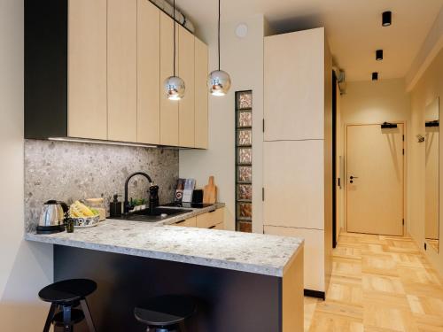 una cocina con armarios blancos y una barra con taburetes en Stereo House by Larsen, en Tallin