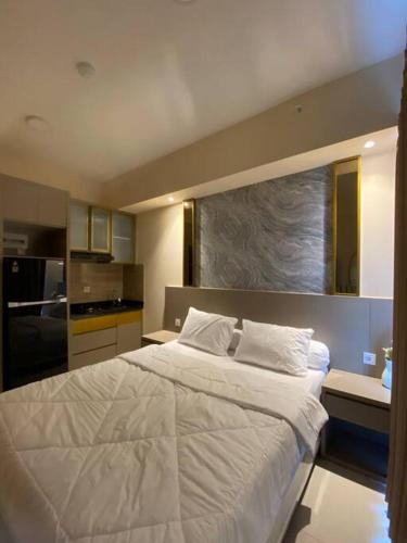 a bedroom with a large white bed and a kitchen at Luxury Studio Benson Apartment, Pakuwon Mall in Surabaya