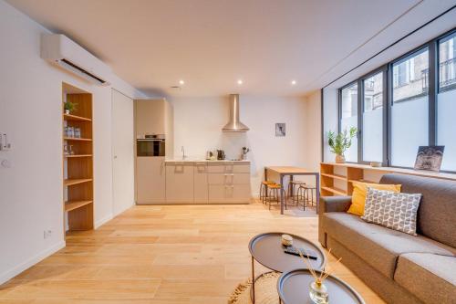 un salon avec un canapé et une cuisine dans l'établissement Les Capucines - Bel appt en centre-ville, à Bordeaux