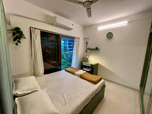 La Olive 1 BHK Service Apartment في مومباي: غرفة نوم صغيرة بها سرير ونافذة