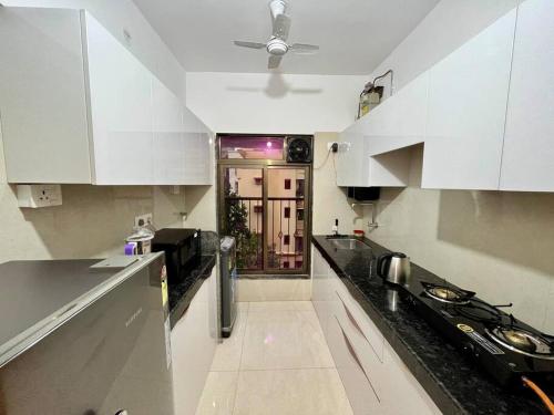 una cucina con armadi bianchi e piano di lavoro di La Olive 1 BHK Service Apartment a Mumbai