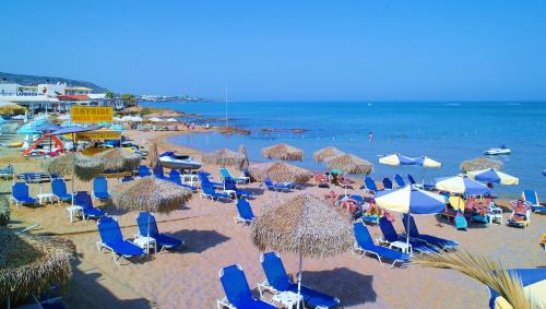 a beach with chairs and umbrellas and the ocean at Camelot Royal Beds by Estia in Malia