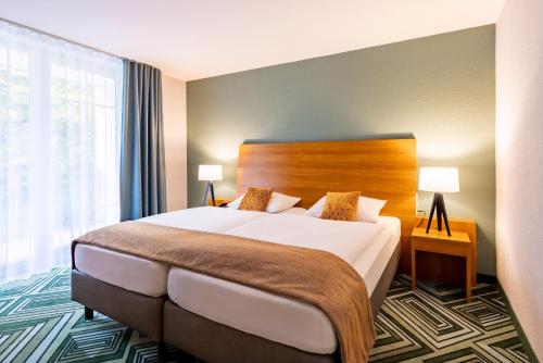 a hotel room with a bed and a large window at Best Western Plus Parkhotel Maximilian Ottobeuren in Ottobeuren
