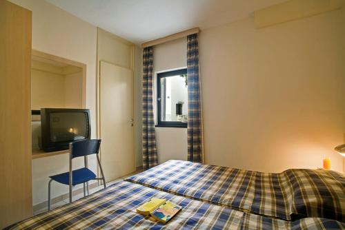 um quarto com uma cama, uma cadeira e uma televisão em Valamar Diamant Residence em Porec