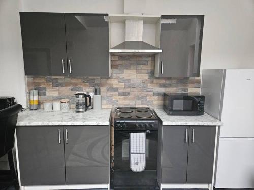 a kitchen with a stove and a microwave at LUXE Villa Near NEC, BHX & Train in Birmingham