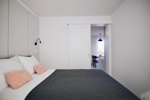 a white bedroom with a bed and a desk at Malinska Green Apartments in Malinska