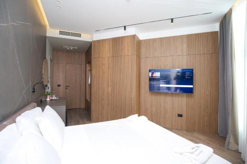 a bedroom with a bed and a tv on a wall at Charm Hotel in Vlorë