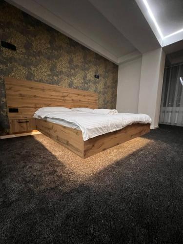a bedroom with a large bed with a wooden headboard at Apart Hotel Bishkek in Bishkek