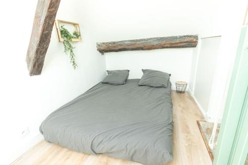 Ce lit se trouve dans une chambre blanche dotée de parquet. dans l'établissement Immeuble L'Aristocrate - Le Boho- Bd Carnot, à Angers