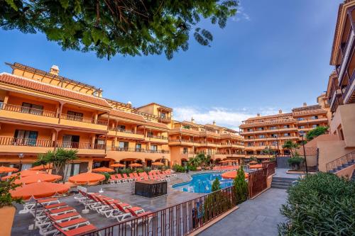 a resort with a swimming pool and orange umbrellas at Coral Los Alisios in Los Cristianos