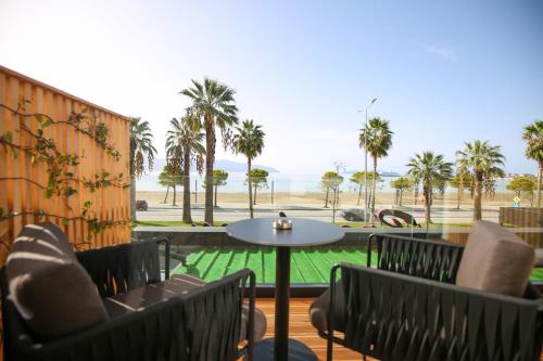 eine Terrasse mit Stühlen, einem Tisch und Palmen in der Unterkunft Charm Hotel in Vlorë