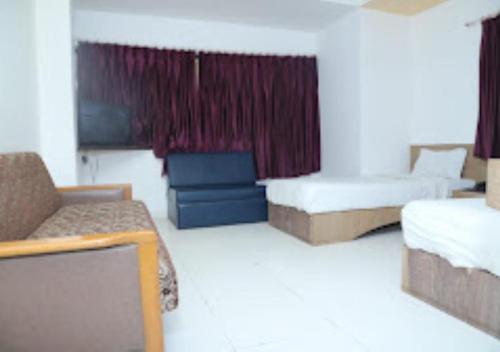 a hotel room with two beds and a couch at Hotel Kewal INN Jalgaon in Jālgaon