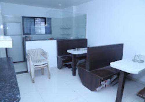 a white kitchen with a table and a chair at Hotel Kewal INN Jalgaon in Jālgaon