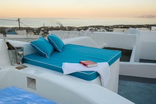 Una cama con almohadas azules y una botella de vino. en Santorini traditional 1Bd apt with private hot tub en Fira