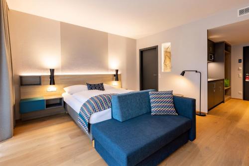 a hotel room with a bed and a blue couch at Best Western Plus Parkhotel Maximilian Ottobeuren in Ottobeuren