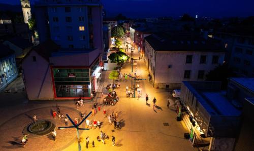 a group of people walking down a street at night at Hotel GOLD JET Bihać in Bihać