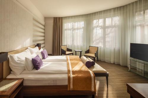 a hotel room with a bed and a flat screen tv at Grand Hotel Glorius Makó in Makó