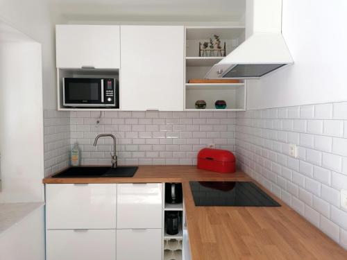 uma cozinha branca com um lavatório e um micro-ondas em La Source, location saisonnière proche Cognac em Saint-André