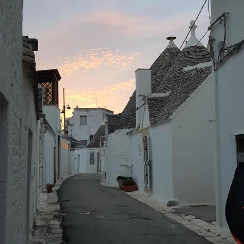 an alley with white buildings and a clock tower at La casetta di zia Giuseppina in Alberobello