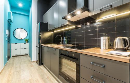 una cocina con electrodomésticos de acero inoxidable y azulejos negros en Rent like home - Gąsiorowskich 8 en Poznan