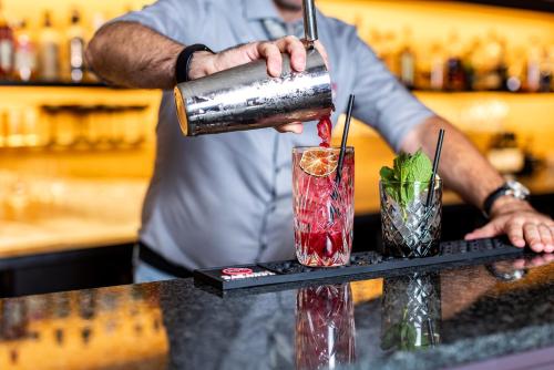 a bartender is making two cocktails on a bar at Best Western Plus Parkhotel Maximilian Ottobeuren in Ottobeuren