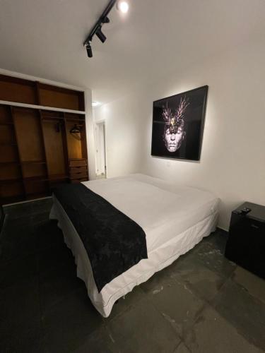 um quarto com uma cama grande e uma fotografia na parede em Acomodações do Tio Will - 2 no Guarujá