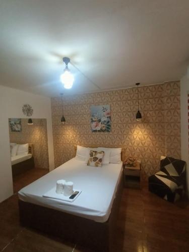 een slaapkamer met een wit bed en een stoel bij DJCI APARTELLE in Cabanatuan