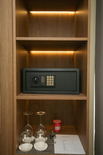 a microwave oven in a cabinet with two glasses at Charm Hotel in Vlorë