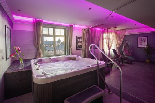 a large bathroom with a tub with purple lighting at Grand Hotel Glorius Makó in Makó