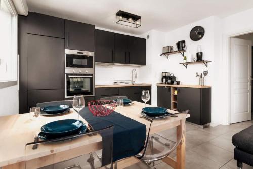 uma cozinha com armários pretos e uma mesa com pratos em Apt moderne & Confortable - Parking free em Toulouse